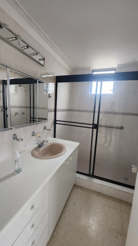 Small bathroom with white vanity, mirror, glass shower enclosure PH Park City Panama City