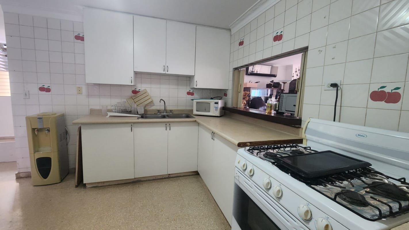 White kitchen cabinets with apple motif tiles double sink in Park City Panama City