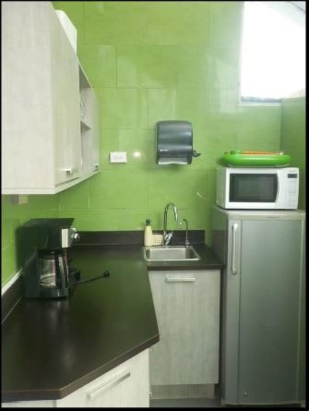 Small kitchenette with green tile walls and appliances in PH Molon Tower commercial property Panama City