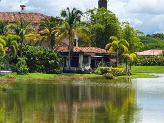 Mediterranean-style villa with red tile roof and palm trees by the lagoon in Buenaventura Resort Panama