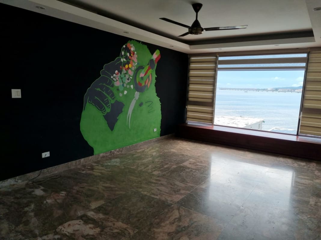 Living room with marble floors, graffiti mural wall, large ocean view windows in PH Maresias Punta Paitilla Panama