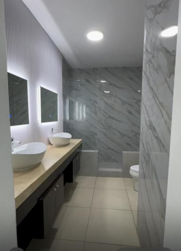 Modern bathroom with marble tiles, double sinks, glass shower at PH Destiny in Panama City