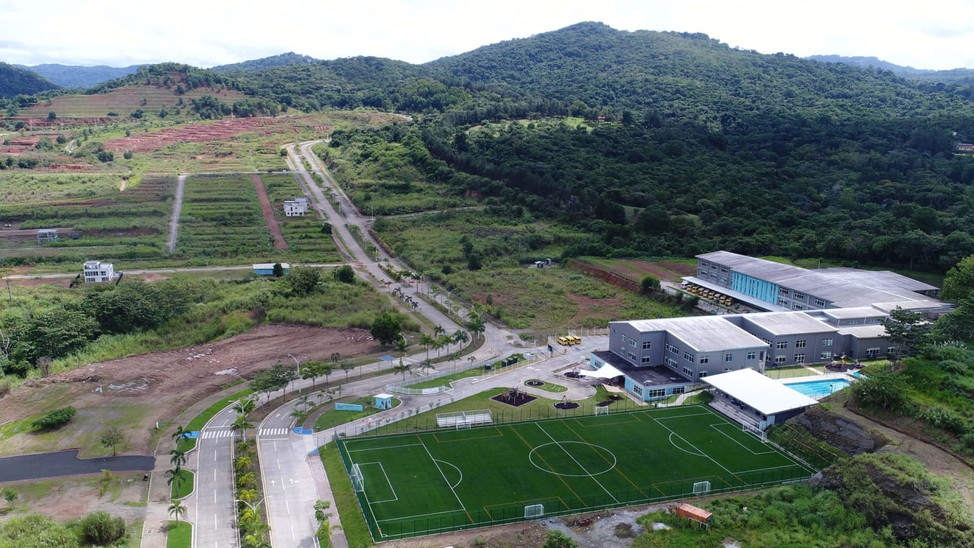 Aerial panorama of school and sports areas amidst greenery and mountains in Green Valley Panama