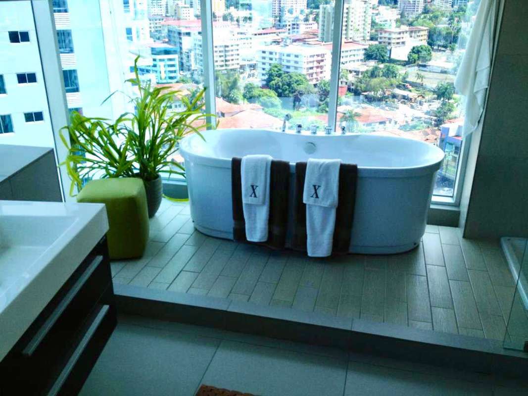 Modern bathroom with freestanding bathtub near large windows overlooking Panama City
