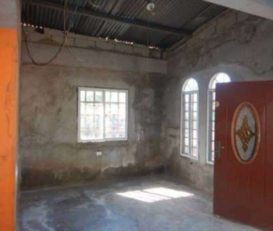 Simple unfinished living area with concrete walls in affordable Pacora house