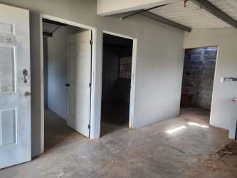 Unfinished concrete hallway with white doors and exposed beams inside affordable house La Chorrera