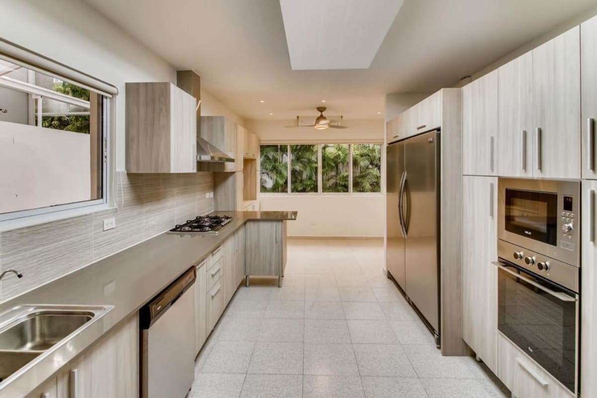 Minimalist kitchen with large windows, stainless appliances, skylight and wood cabinetry in Costa del Este luxury home