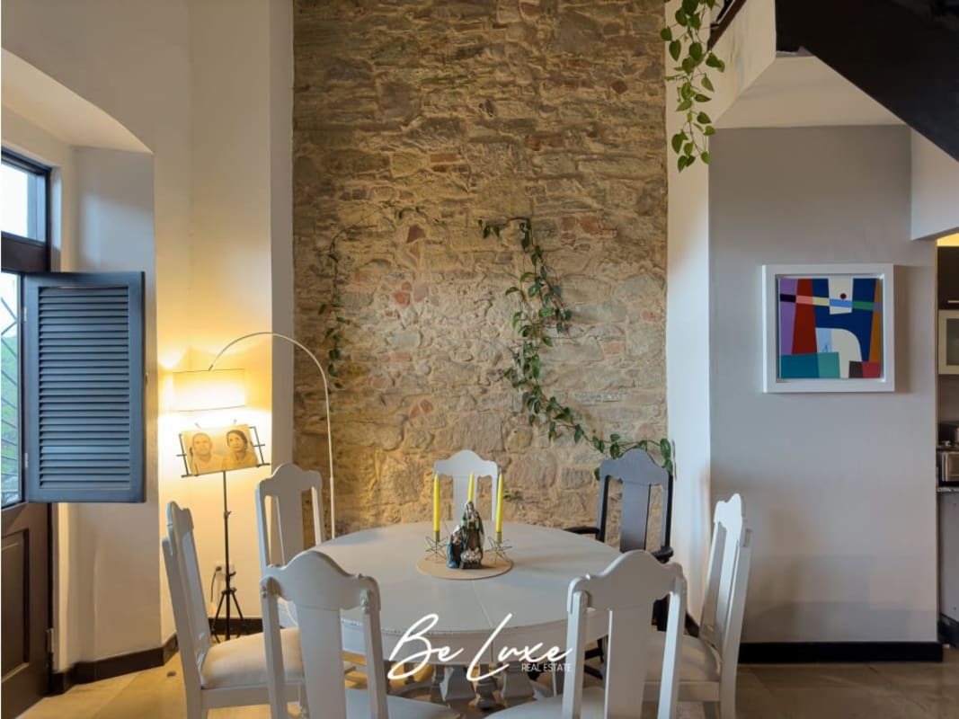 Dining area with exposed stone wall and arched shuttered windows in loft apartment Casco Viejo