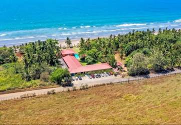 Aerial shot of beachfront hotel showing red roofs, lush gardens, beachfront pool in Playa Las Lajas Panama