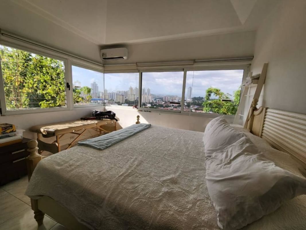 Bedroom with large corner windows showcasing skyline, AC, and spacious design Betania Panama