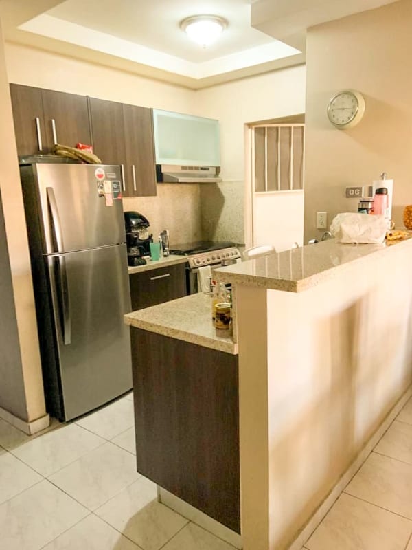 Bedroom with beige upholstered bed, wood floor, and large window in remodeled San Antonio home
