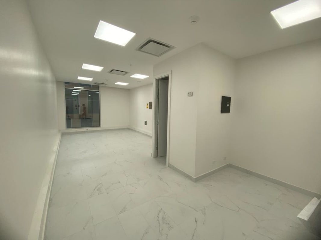 Spacious empty office with white walls, marble floor tiles, recessed lighting, glass partition walls in TownCenter Costa del Este