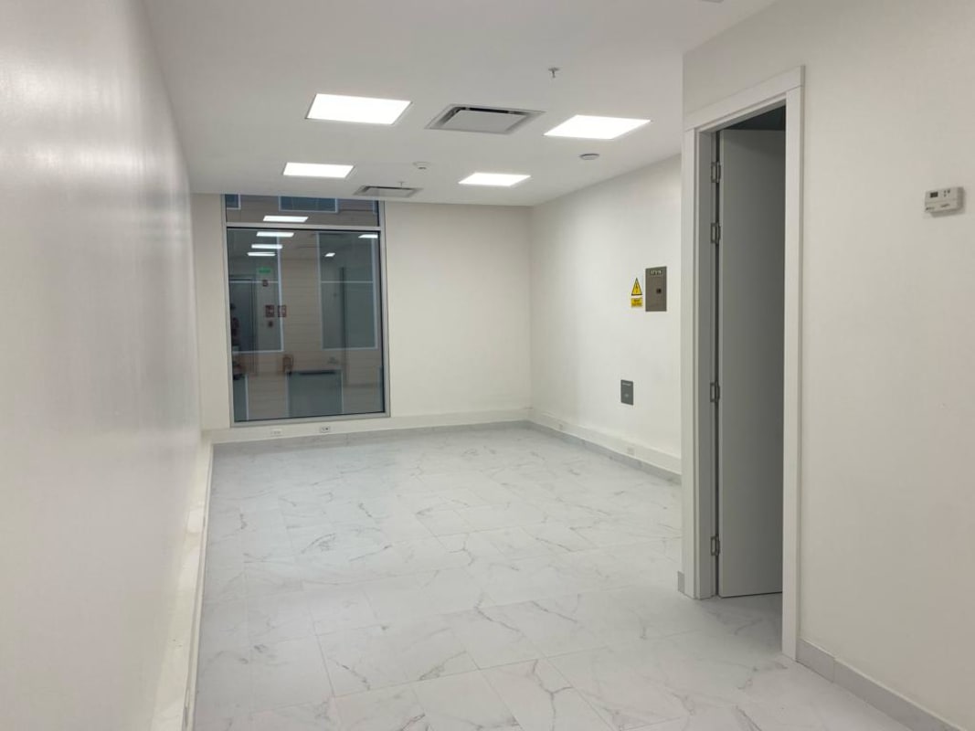 White empty office space with recessed lights, marble floors, AC vents and large glass window in Costa del Este