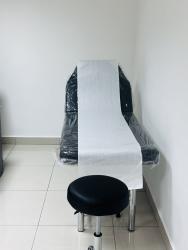 Plastic-covered exam table and stool in clinical minimalist room inside Hospital Chiriquí Tower