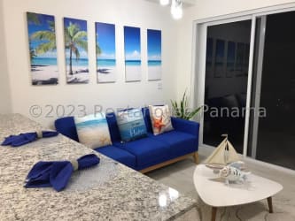 Bright living room with blue sofa, beach decor and terrace access overlooking Pacific Ocean at Playa Caracol Panama