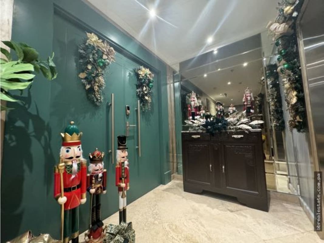 Elegant entry foyer with holiday decor, wood flooring, wall panels in duplex penthouse Costa del Este