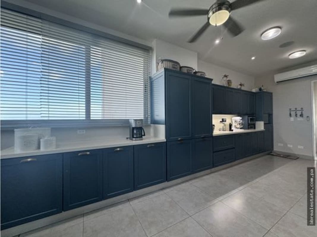Modern kitchen with blue cabinets, stainless steel oven, white countertops in penthouse apartment Costa del Este