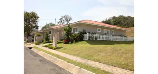 One-story ranch-style house with red tile roof, white fence, and front lawn at Villas del María Bejuco Panama