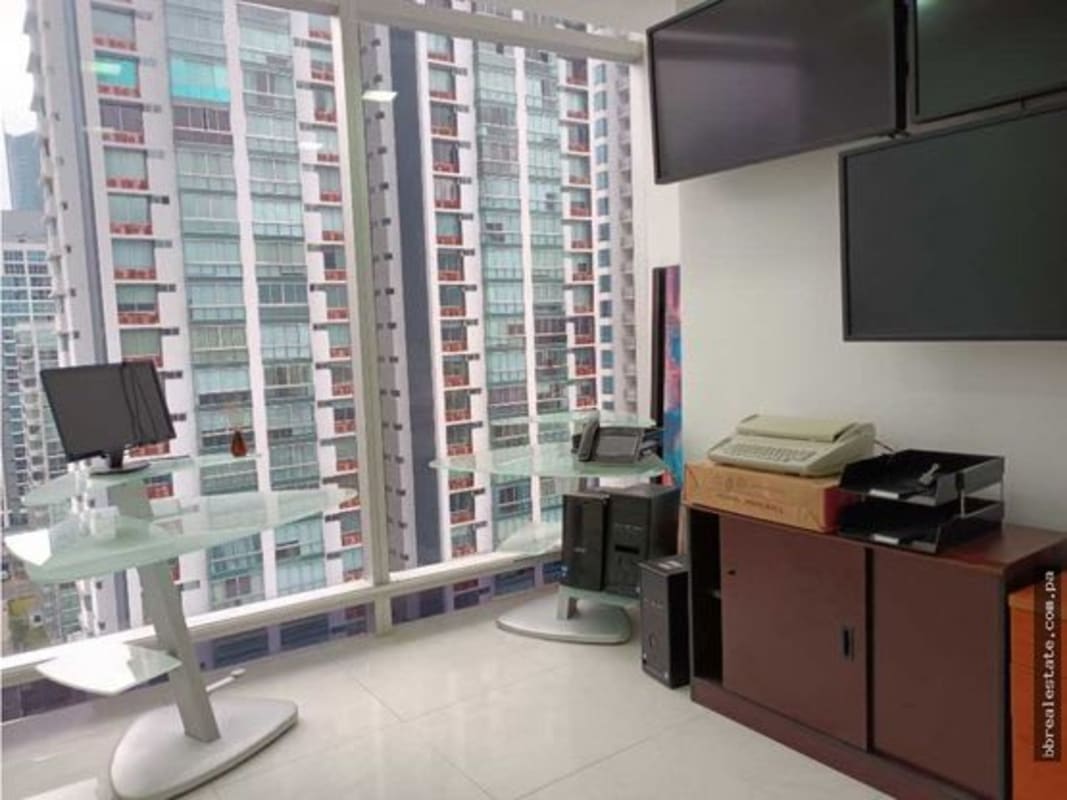 Furnished private office with cityscape views, glass desks, and mounted monitors in Torre Ancón Costa del Este