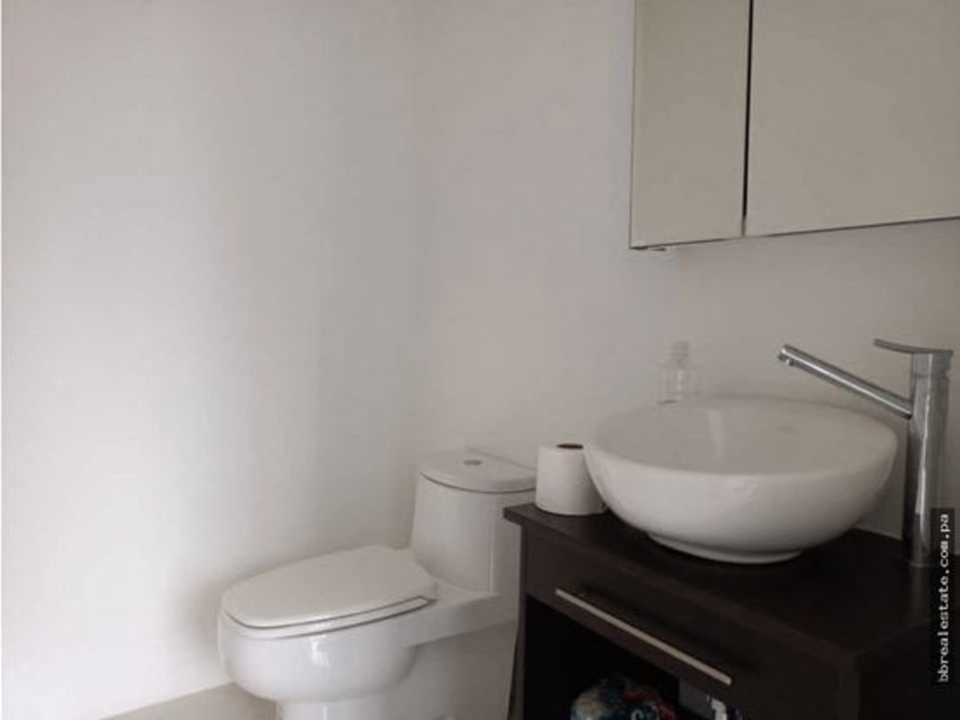 Minimalist corporate bathroom with vessel sink and dark wood cabinet in Torre Ancón Panama