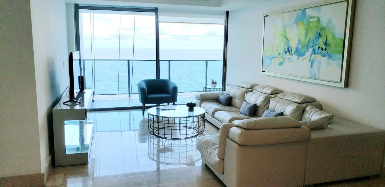 Stylish living room with floor-to-ceiling windows, balcony access, cream sectional sofa and oceanfront views Grand Tower