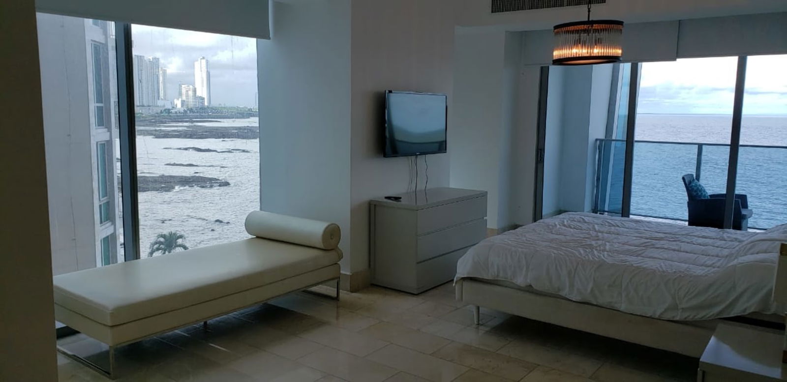 Luxurious master bedroom with large windows, balcony, ocean views in Grand Tower Punta Pacifica Panama