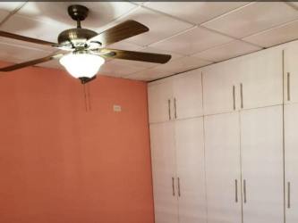 Bedroom interior with peach wall, built-in wardrobes, ceiling fan for house in La Chorrera