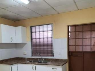 Basic kitchen setup with double sink, wall cabinets, metal grid window in Panama house