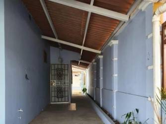 Covered outside corridor with blue wall, tiled floor, security door in suburban Panama house