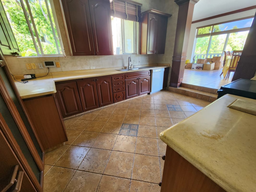 Spacious kitchen with wood cabinets, adjacent dining, garden views in Altos del Golf estate Panama
