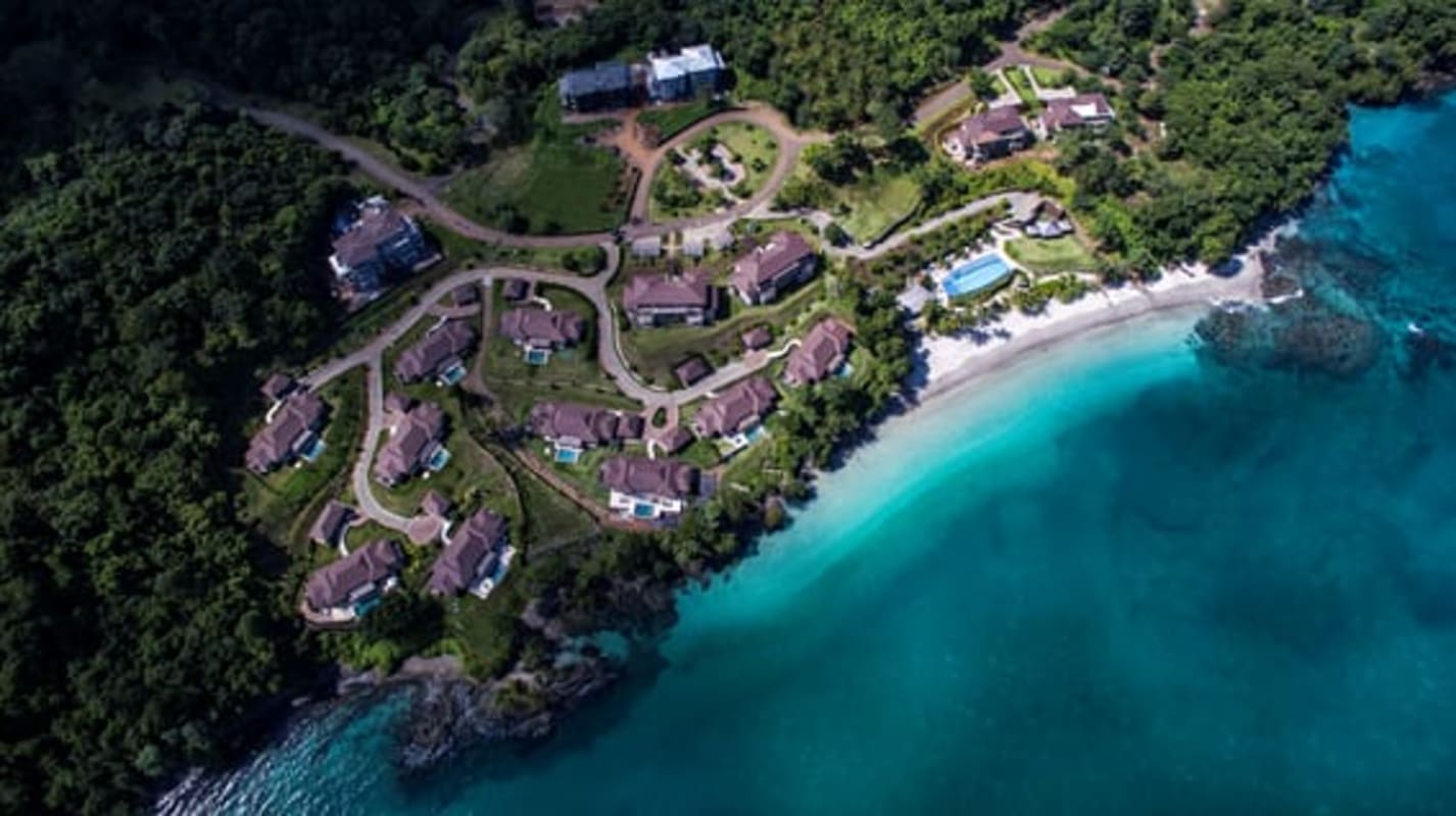 Tropical island aerial view showcasing beachfront condos, marina and lush vegetation in Las Perlas Panama