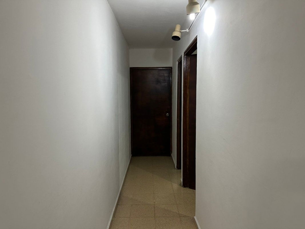 Long hallway white walls tiled floors dark wood doors PH Plaza del Golf Panama