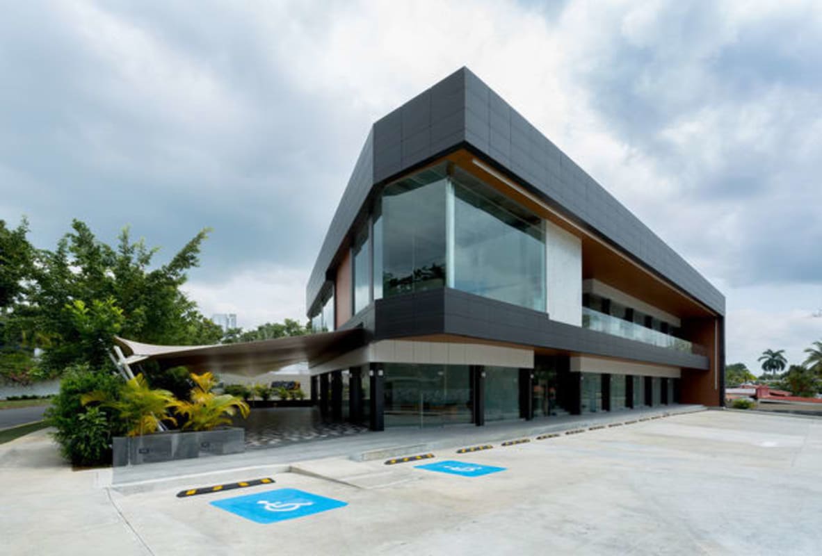Modern two-story commercial building with glass facade and parking at Plaza Santa Elena Altos del Golf Panama City