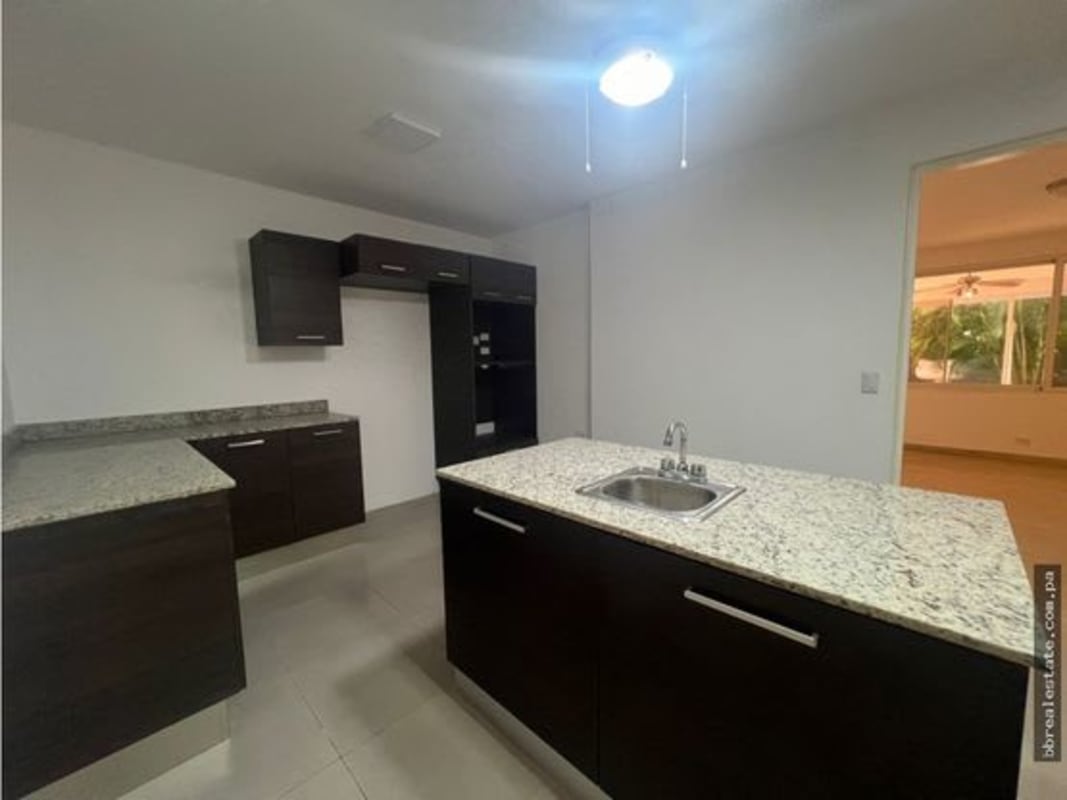 Spacious kitchen with granite countertops, wood cabinets, and tile flooring in Punta Paitilla residence