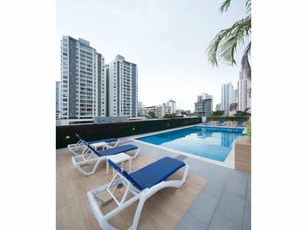 Frameless glass shower with rainfall head and wood tile accent wall in apartment bathroom Panama City