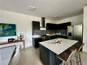 Kitchen island with black cabinetry, stainless steel appliances, dining space PH River Valley condo