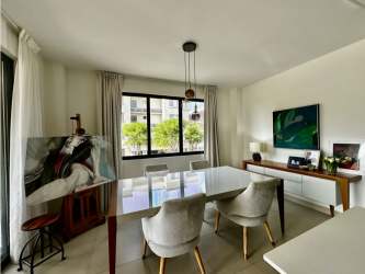 Dining room with glass table, upholstered chairs, bright windows in condo Panama Pacifico