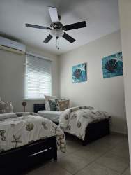 Twin beds with coastal decor, ceiling fan, light blue tones in Bijao Resort condo Panama