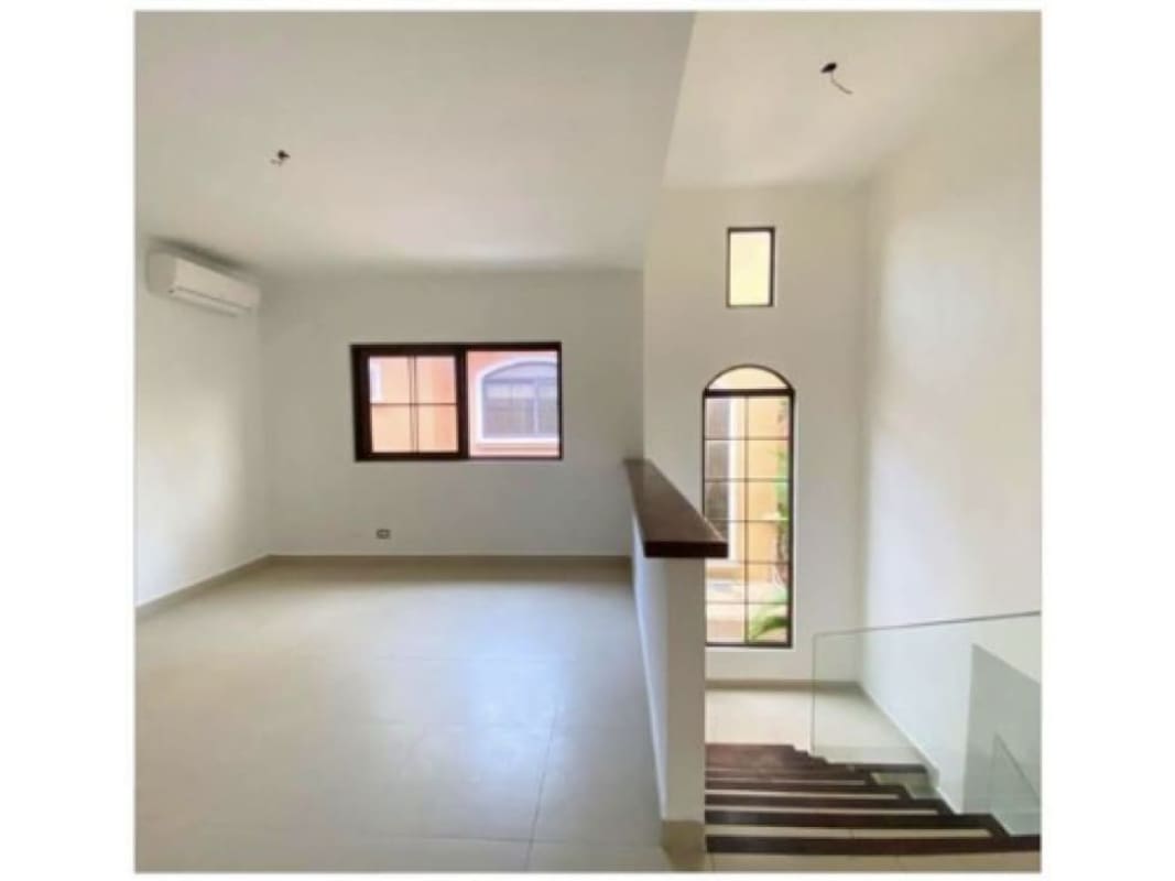 Modern staircase with glass railings, large arched window providing natural light, open plan in El Doral Costa Sur Panama