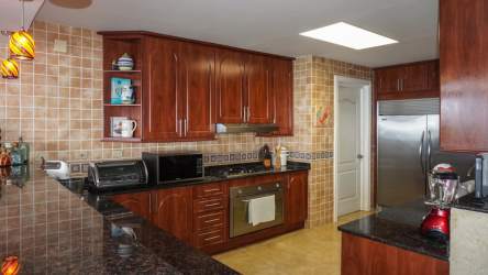 Kitchen with granite countertops, wood cabinets, stainless appliances in PH Miramar Farallón Beachfront Condo Panama