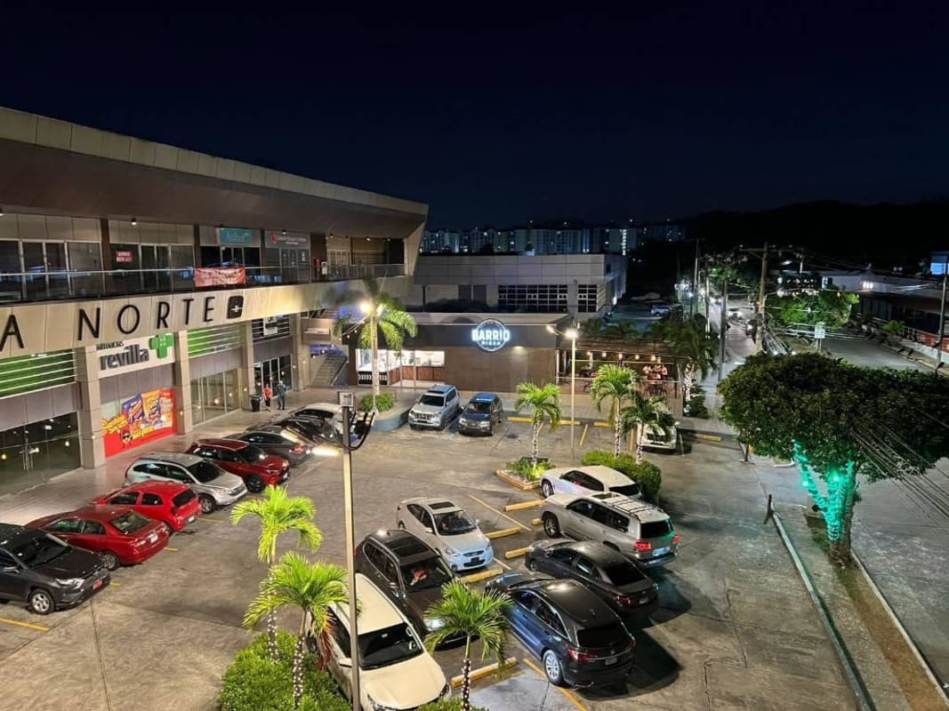 Altos Plaza commercial space exterior with palm trees, multiple storefronts, parking lot illuminated at night in Condado del Rey Panama City