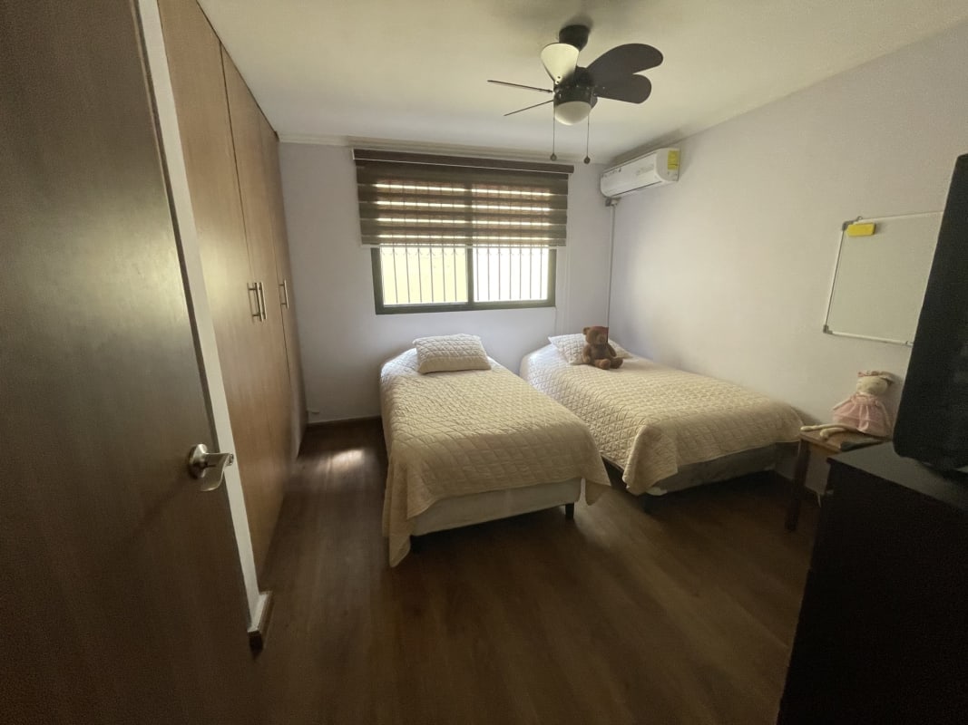 Contemporary bedroom with wooden floor and twin beds in Panama City house