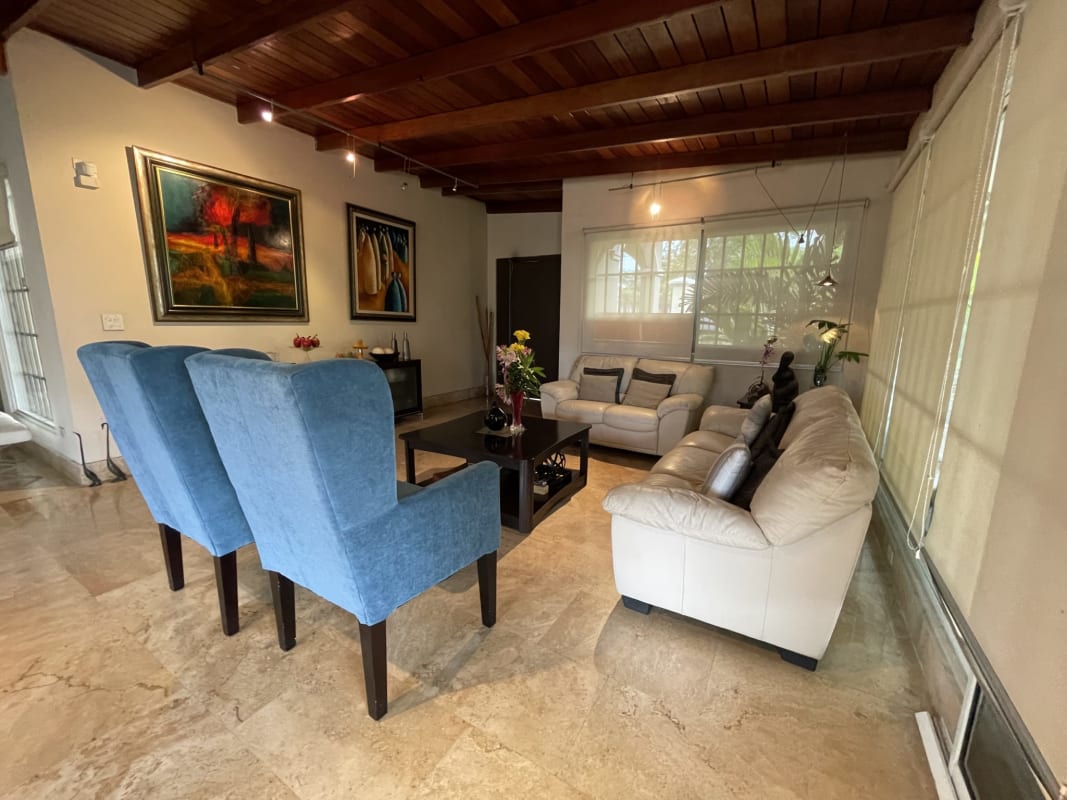 Master bedroom with exposed beams, green accent wall, garden view in Altos del Golf San Francisco Panama