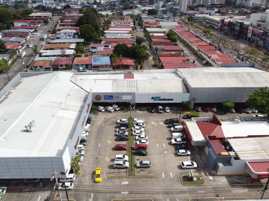 Overhead view of busy commercial shopping center with parking and adjacent neighborhood in Panama City