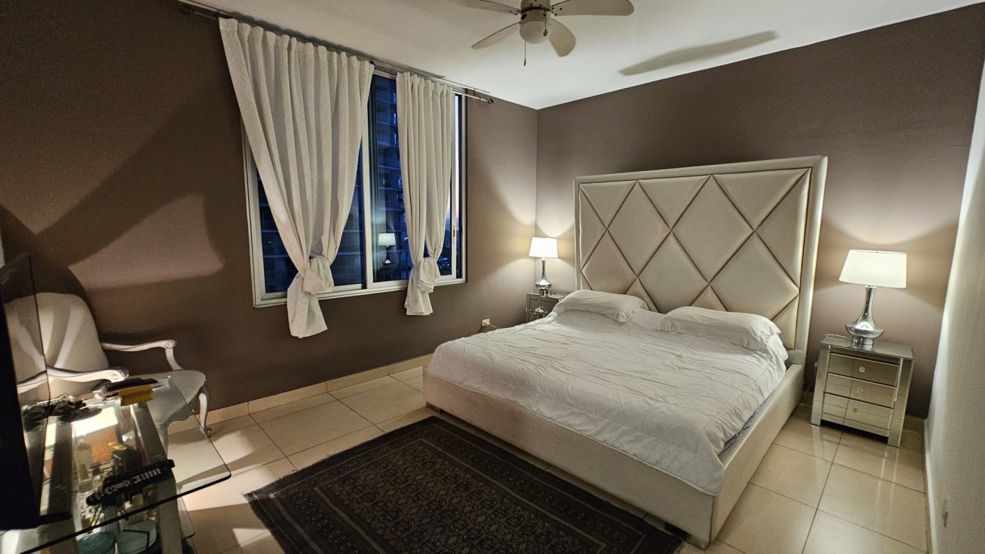 Spacious master bedroom featuring upholstered headboard, city skyline view, and luxurious finishes at PH Sky Residence Panama