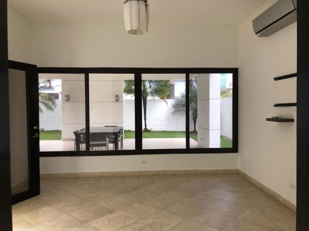 Modern living space with floor-to-ceiling windows overlooking private garden in Costa del Este rental house Panama City