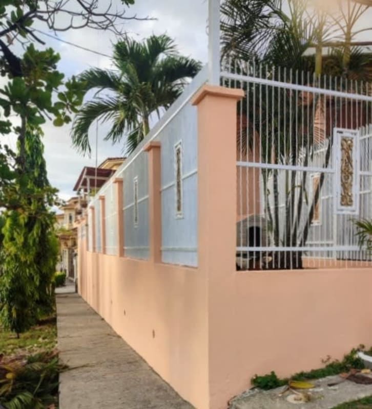 Peach color wall white iron fence tropical plants palm trees house PH Villa de Vizcaya Condado del Rey Panama