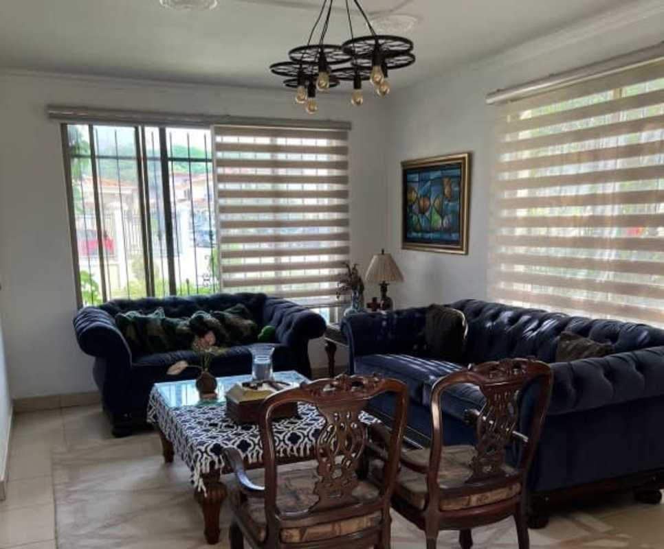 Bright living room with navy sofas, chandelier and large windows at Condado del Rey home