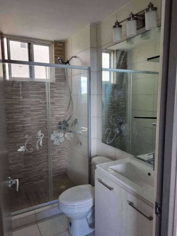 Bright modern bathroom with glass-enclosed shower, vanity and window in apartment for sale Panama City