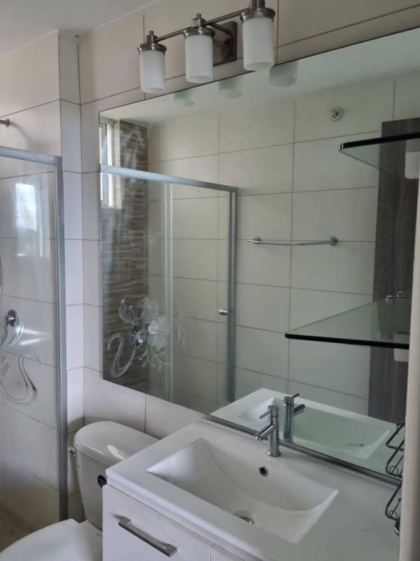 Elegant bathroom with glass shower, tiled walls, vanity at Torres de Cantabria Spain in Panama